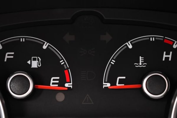 Detailed view of a car's fuel and temperature gauges on dashboard.